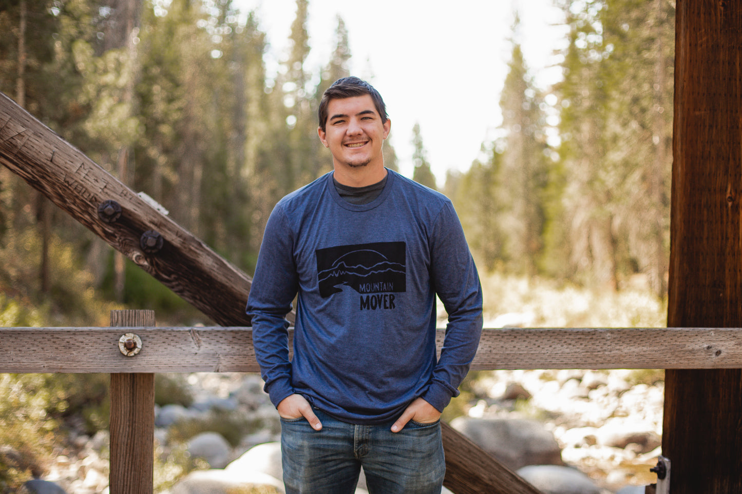 Man in navy mountain mover tee with black stamp depicting a mountain scene