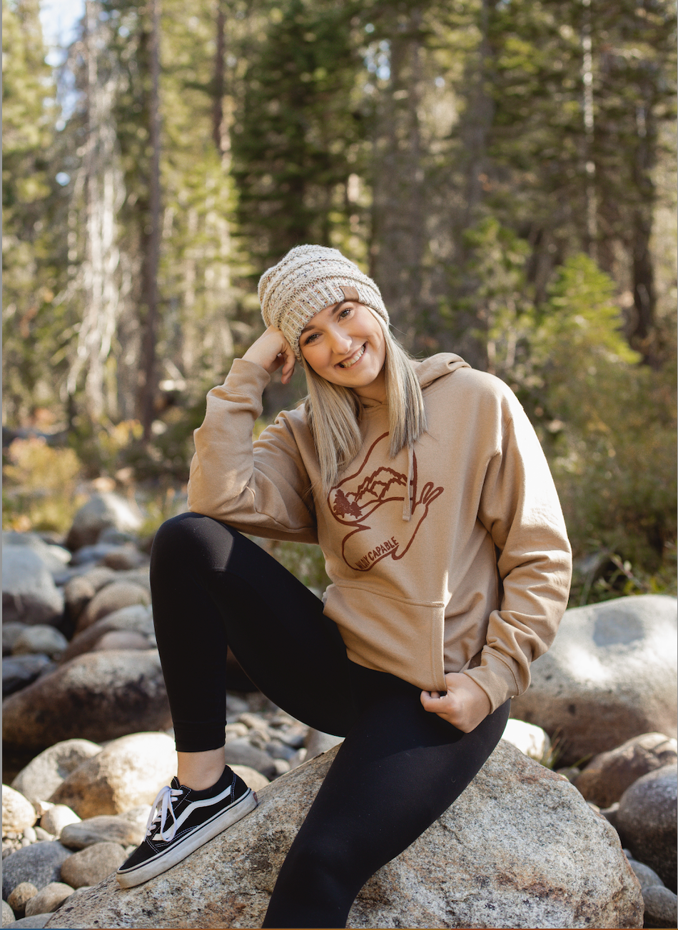 Woman in tan hoodie with wildly capable butterfly logo