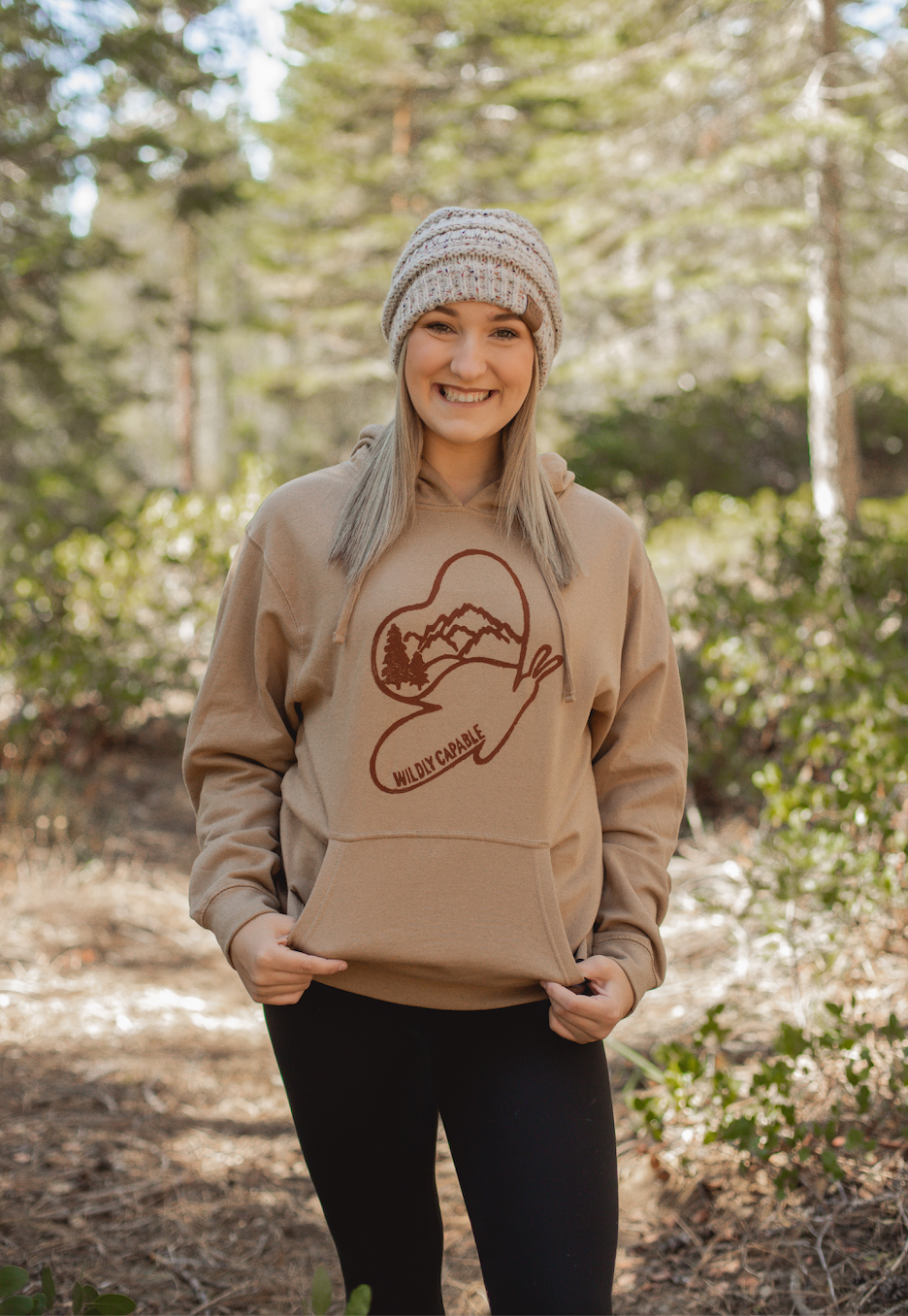 Woman in tan hoodie with wildly capable butterfly logo