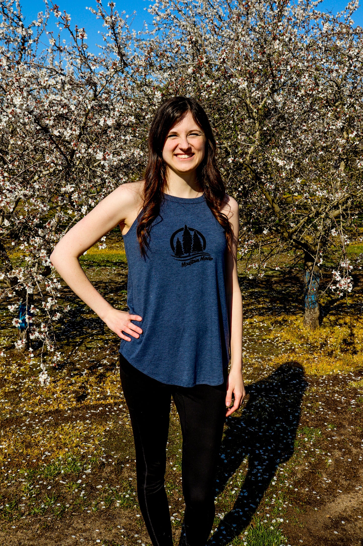 woman wearing navy blue tank with black three tree stamp and mountain mover written beneath